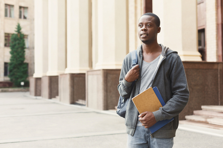 Pensive african-american student with books outdoors, looking away, dreaming or thinking during break, having rest in campus. Education concept, copy spaceの写真素材