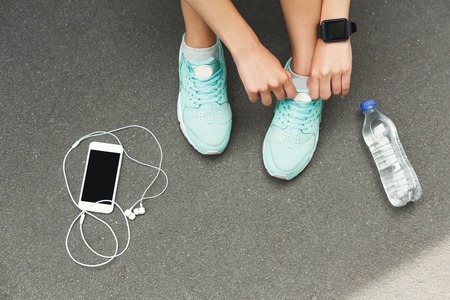 Woman tying shoes laces before running, getting ready for jogging in park, top viewの写真素材