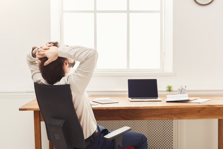 Successful business background. Relaxed businessman taking rest in modern office, back view with copy spaceの写真素材