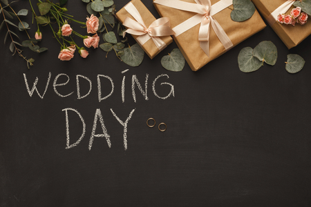 Border of wedding present boxes, rose bouquet, leaves, rings and written text on black background. Memmorable date organization concept, top viewの写真素材