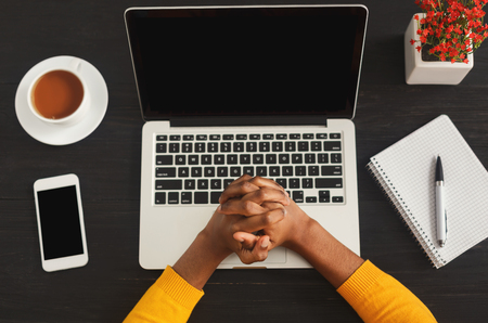 African-american female clenched hands over office desktop. Black woman working space with laptop, smartphone and notepad, top view, copy space. Education, business, technology conceptの写真素材