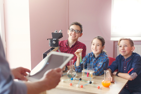 Teenagers listening to teacher talking about chemistry in laboratory, sitting with reagents and microscope. Stem education. Early development, education, diy, innovation conceptの写真素材