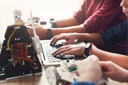 Children creating robots at school, stem education, copy space. Hands typing on keyboard, closeup....