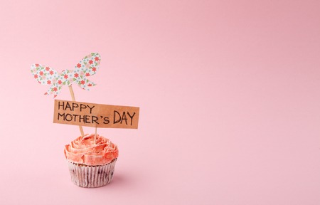 Mothers day background, handmade greeting card in tasty cupcake at tender pink backdrop. Present for mommy, copy spaceの写真素材