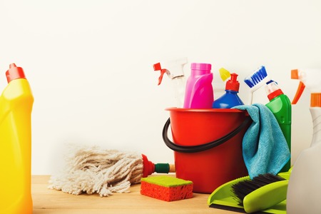 Variety of house cleaning products on wood table at white background, closeup. Bucket, brush, rubber gloves, mop, disinfection items and other. Tidying up, spring-cleaning concept, copy spaceの写真素材