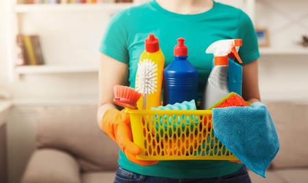 Young woman holding bucket with group of cleaning supplies for natural and environmentally friendly cleaning. Household equipment, spring-cleaning, tidying up, cleaning service concept, copy spaceの写真素材