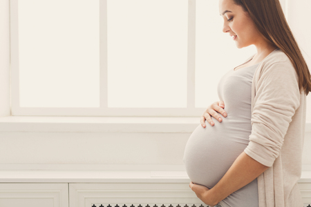 Pensive pregnant woman dreaming about child. Young happy expectant thinking about her baby and...