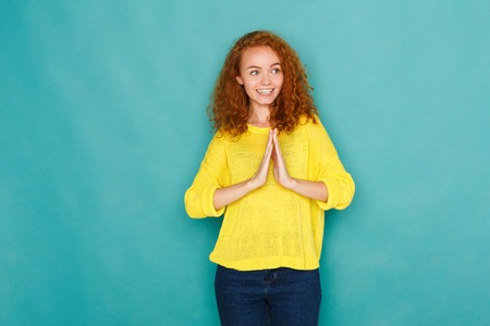 Cheerful relaxed woman with happy face, showing welcome and thank you hand sign, standing on blue...