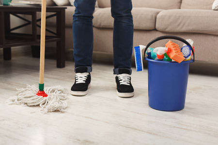 Unrecognizable man ready to clean. Crop of male legs with mop and plastic bucket with cleaning supplies standing near. Household and cleaning service background, copy spaceの写真素材