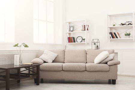 Beige couch with pillows in white modern interior, copy space on window background. Contemporary apartment designの写真素材