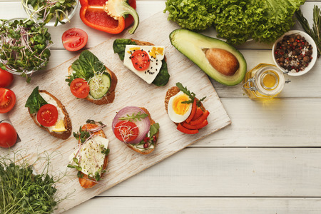 Set of healthy bruschettas with various toppings, top view. Making veretarian sandwiches with soft cheese, organic vegetables, spices and greens. Food background, copy spaceの写真素材