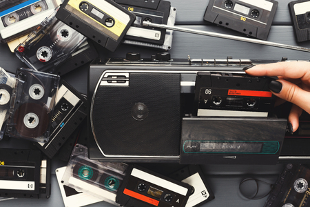 Heap of retro audio cassettes and vintage tape recorder on gray background. Top view on old-fashioned media devices, copy space, flat layの写真素材