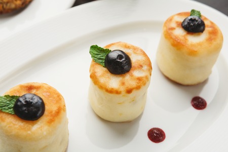 Sweet restaurant breakfast with cheese pancakes, croissants, yogurt and freshly brewed tea served on black table. Nourishing morning mealsの写真素材