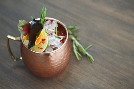 Traditional cocktail in modern serving. Soft drink with vodka, ginger beer and lime juice. Cold beverage in copper cup on wooden table with copy space. Mockup for moscow mule recipeの写真素材
