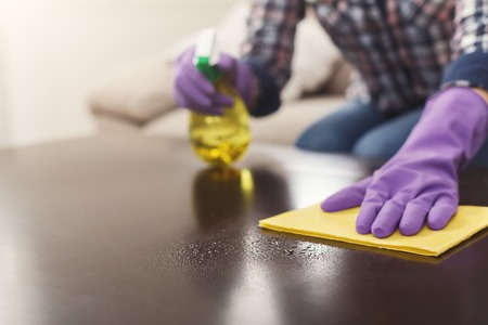 Woman using spray cleaner on wooden surface. Unrecognizable girl polishing furniture, housework and...