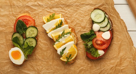 Vegetarian wholegrain sandwiches with micro greens on craft parchment. Vegan party food table with...