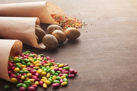Easter composition with golden quail eggs and small colorful chocolate candies in craft paper...