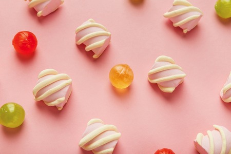 Closeup of marshmallows and colourful sweets on pink background, flat lay. Confectionery store advertisement and sweet life concept.の写真素材