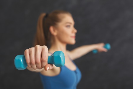 Strong fitness woman training with dumbbells at gym, doing strength exercise for biceps, bodybuilding concept, copy spaceの写真素材