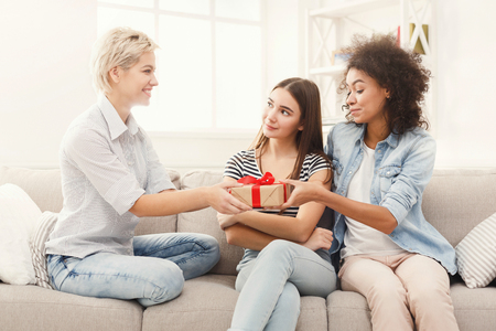 Happy girls exchanging gifts. Excited woman getting present from her friends. Birthday, holidays, celebration and female friendship concept, copy spaceの写真素材