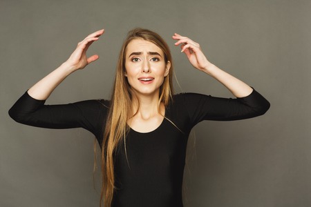 Shocked woman with arms up in air in full disbelief. Surprised girl portrait, dark background. Omg, wtf, human emotions conceptの写真素材
