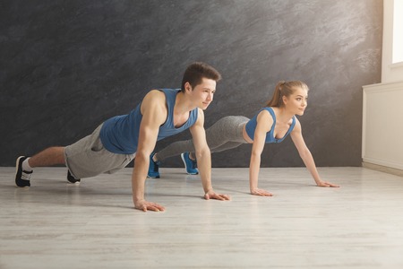 Young man and woman workout in fitness club. Fitness couple making plank or push ups exercise,...