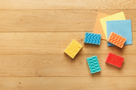 Set of colorful sponges and micro fiber rags on wooden background, top view. Spring cleaning and household concept. Mockup for advertisement with copy space, flat layの写真素材