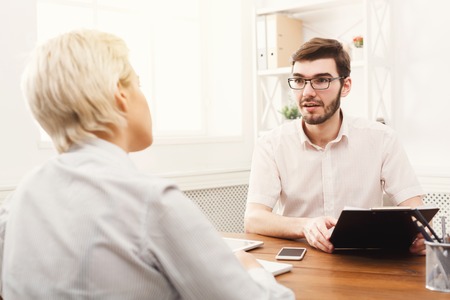 Serious couple of young colleagues working in modern office. Two coworkers discussing their project, working with documentsの写真素材