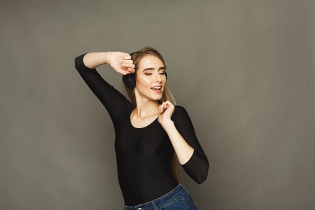 Favorite song. Woman dancing and enjoying music in earphones with closed eyes, standing on brown studio backgroundの写真素材