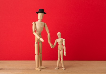 Wooden mannequins as father and son symbols against red background. Education, upbringing, parents and children conceptの写真素材