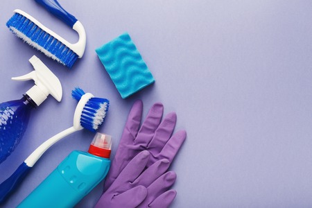 Spring cleaning background. Assortment of colorful spray detergents, sponges, rags and other supplies isolated on violet. Cleaning services and tidying up concept, top view, copy spaceの写真素材