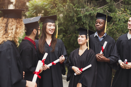 A group of multietnic students celebrating their graduation. Education, qualification and gown concept.の写真素材