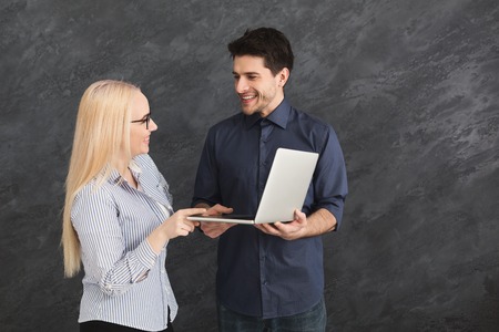 Happy couple shopping online, making order with laptop, gray studio background, copy spaceの写真素材