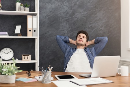 Happy relaxed businessman in office. Handsome man having rest at workplace, dreaming about something, copy spaceの写真素材