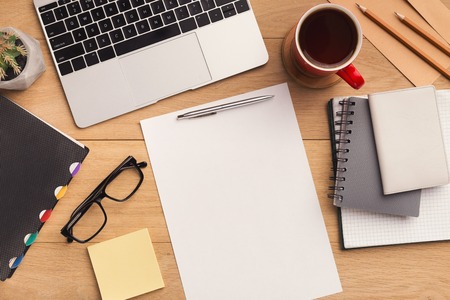 Male workplace with empty sheet of paper for advertisement, laptop, coffee cup, notebook and...