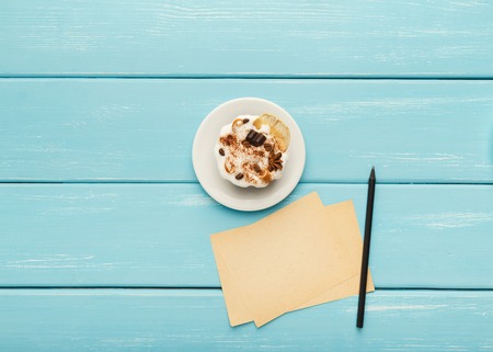 Delicious chocolate cake on white plate, pen and small papers for romantic messages on turquoise wooden table, top view, copy spaceの写真素材