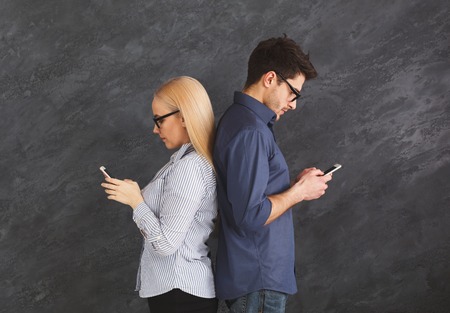 Young couple in love ignoring each other with phones, modern technologies and gadget addiction...