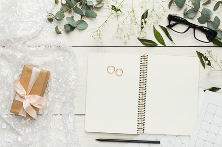 Wedding background with checklist. Paper planner and wedding rings on white wooden table with lots of tender bridal stuff, top viewの写真素材
