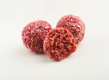 Whole and cut vegan chocolate candy in red coconut flakes isolated on white background, cutoutの写真素材