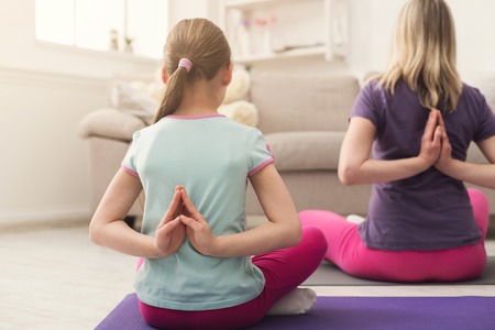 Young woman and child daughter training and stretching at home. Support, trust, lifestyle, fun, maternity concept.の写真素材