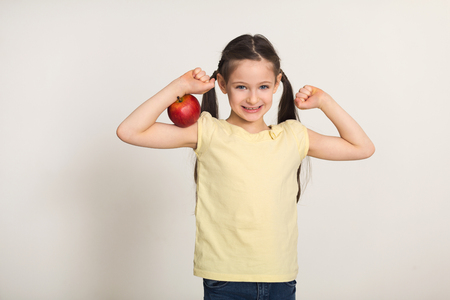 Pretty cute little girl standing with red apple over white background. Healthy food for children conceptの写真素材