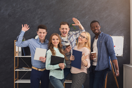 Cheerful business people in office. Successful young team posing for photo, greeting and smiling at camera, motivation and success concept, copy spaceの写真素材
