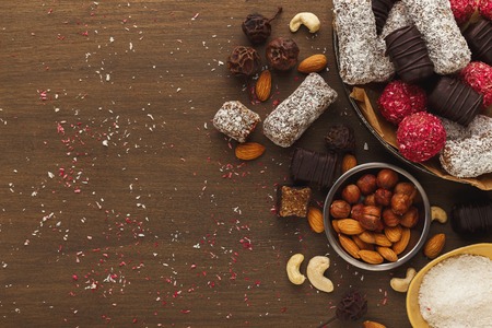 Top view on wooden table with variety of healthy raw vegan candies, almonds, hazelnuts, dates. Fitness dessert and eating right concept, copy spaceの写真素材