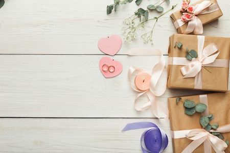 Wedding craft gift boxes on white wooden background. Top view on ribbons, flowers and scissors, copy space. Memmorable date organization conceptの写真素材