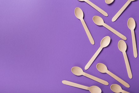 Top view on many bamboo spoons on violet background, copy space. Disposable take away table wear conceptの写真素材