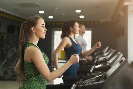 People run on treadmills. Men and women cardio workout in fitness club. Healthy lifestyle, training in gym, copy spaceの写真素材