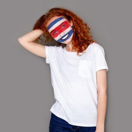 Face of young happy woman painted with flag of Costa Rica. Football or soccer team fan, sport event,...