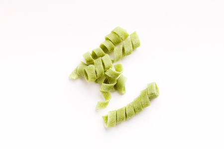 Pile of raw green spinach fusilli pasta isolated on white background. Unusual creative meal, Italian cuisine conceptの写真素材