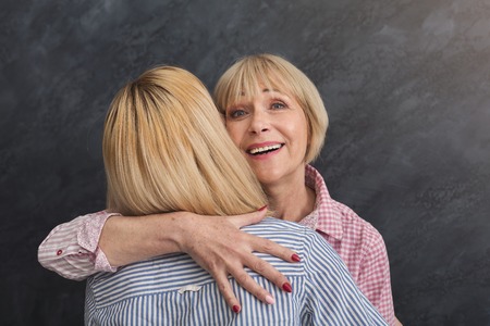 Happy adult mother and daughter embracing on grey background, closeup. Generation and relationship conceptの写真素材
