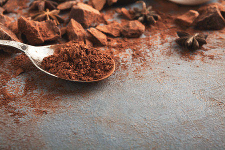 Dark chocolate pieces crushed on dark background and cocoa powder closeup, copy space. Sweet wallpaper, confectionery shop advertising and cooking ingredients conceptの写真素材